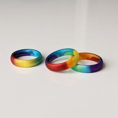 two rainbow colored rings sitting next to each other on a white surface with one ring in the middle