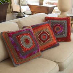 two crocheted pillows sitting on top of a couch