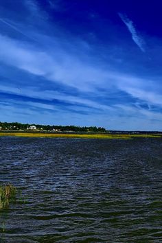 a large body of water sitting under a blue sky with some clouds in the background