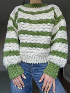 a woman with her hands on her hips wearing a green and white striped knit sweater