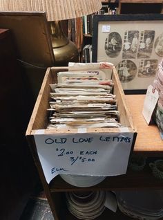 old love letters are stacked in a wooden box on a table next to a lamp