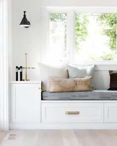 a window seat in the corner of a room with white walls and wooden flooring