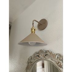 a wall light that is on the side of a white wall next to a mirror