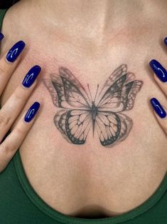 a woman's chest with a butterfly tattoo on her left side and blue nails