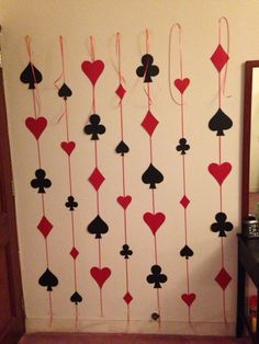 a wall decorated with playing cards and hearts hanging from it's sides in a hallway