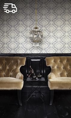 two chairs in front of a fireplace with a chandelier hanging from the ceiling