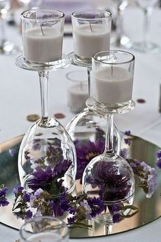 purple flowers and candles are arranged in wine glasses