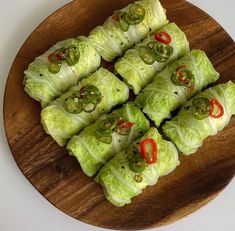 some lettuce wrapped in red peppers on a wooden plate