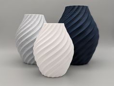 three vases with wavy designs on them sitting side by side in front of a gray background