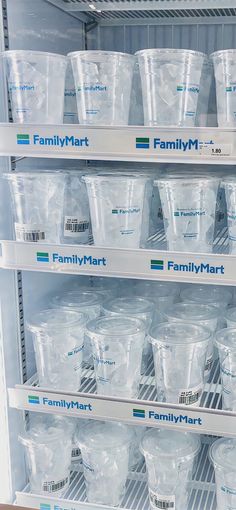 many plastic cups are stacked on shelves in a refrigerator with labels reading familymart and familymart