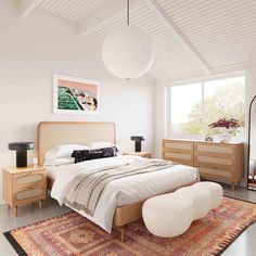 a bedroom with a large bed, dressers and lamps on the wall above it