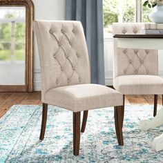 a pair of beige chairs sitting on top of a rug