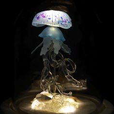 an illuminated jellyfish in the dark with its head turned to look like it is floating