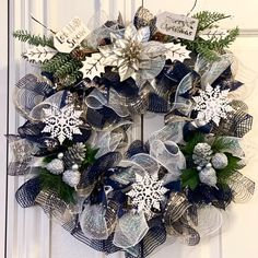 a christmas wreath with snowflakes and evergreen leaves hanging on the front door,