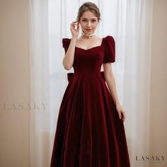 a woman in a red dress posing for the camera with her hand on her head