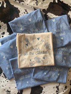 four blue handkerchiefs with hearts and words on them sitting on top of a cow print blanket