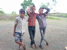 three young boys are standing in the dirt