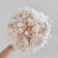 a bridal bouquet with white flowers and baby's breath on it is being held by someone