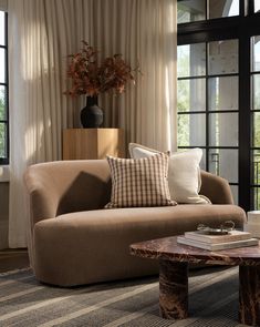 a living room with a couch, table and large window in the back ground area