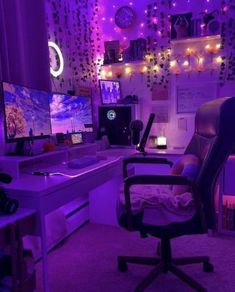 a chair in front of a desk with a computer on it and purple lights hanging from the ceiling