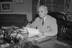 an older man sitting at a desk in front of a book and papers on it