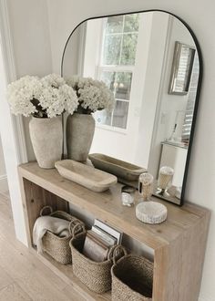 a mirror sitting above a wooden shelf filled with baskets and flowers