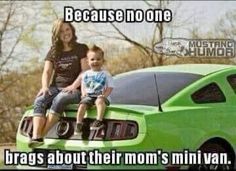 a woman and child sitting on the hood of a green car