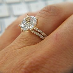 a woman's hand with a diamond ring on top of her finger next to a keyboard