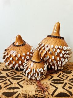 two decorative vases made out of shells on a tablecloth with a white wall in the background