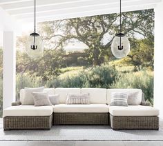 an outdoor living room with white couches and hanging light fixtures on the wall above them