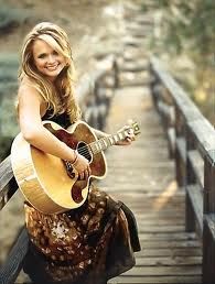 a woman is playing an acoustic guitar on a bridge