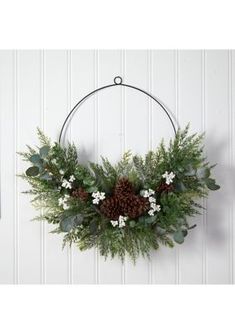 a wreath hanging on the wall with pine cones and greenery