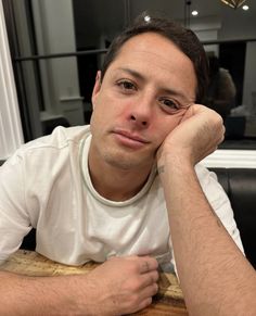 a man sitting at a table with his hand on his chin looking to the side