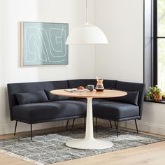 a living room area with a couch, table and lamp on the floor in front of a window