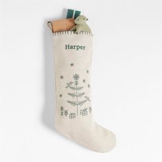 a christmas stocking hanging from the side of a white wall with a green tree on it