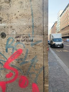 graffiti is spray painted on the side of a concrete wall next to a street with parked cars