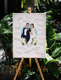 a wedding portrait on an easel in front of some green plants and greenery