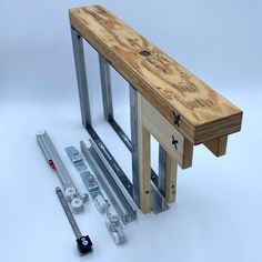 a wooden bench sitting next to some metal bars and screwdrivers on a white surface