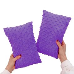 two purple pillows being held up to each other