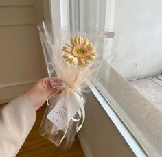 a person holding a bouquet of flowers near a window sill with a tag on it