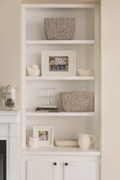 a white bookcase with baskets and pictures on it