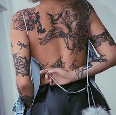 a woman with lots of tattoos on her back and shoulder is holding a fur ball