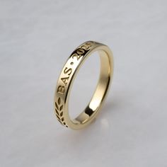 a gold wedding ring with the word boss engraved on it's side, sitting on a white surface