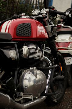 a red and black motorcycle parked on the side of a road next to other motorcycles