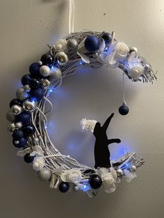 a christmas wreath with blue and white ornaments hanging from the wall next to a light