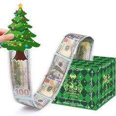 a roll of money with a christmas tree sticking out of it next to a green gift box