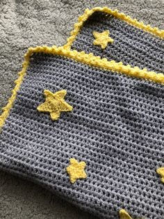 a crocheted blanket with yellow stars on it sitting on a gray carpeted floor