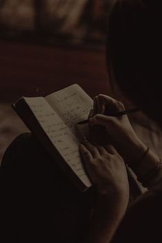 a person writing on a notepad with a pen in their hand and holding a notebook