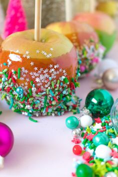 an assortment of colorful candies and apples on a table with christmas decorations around them