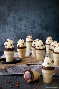 cupcakes with white frosting and chocolate sprinkles are arranged on a table